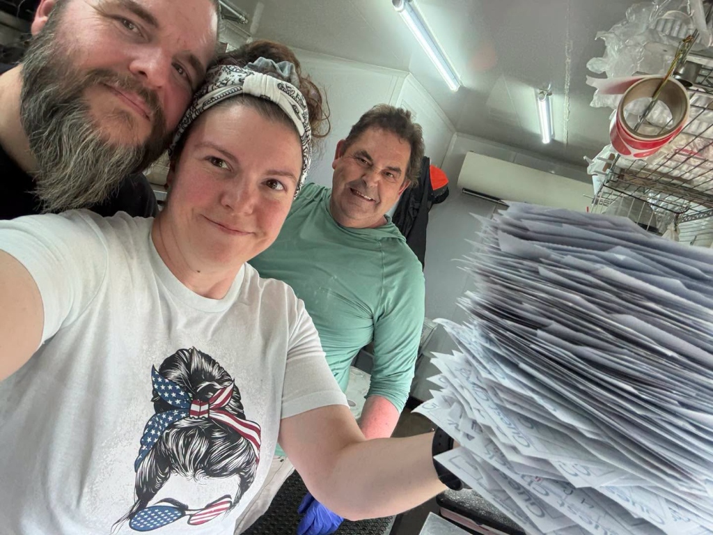 Real Beignet Today owners and team smiling inside the food truck holding guest checks
